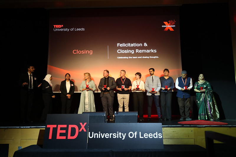 Speakers holding red TEDx awards on stage during the Felicitation & Closing Remarks