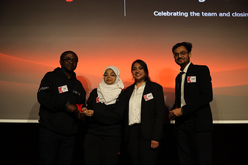 Team members on stage with a red TEDx award during the closing celebration