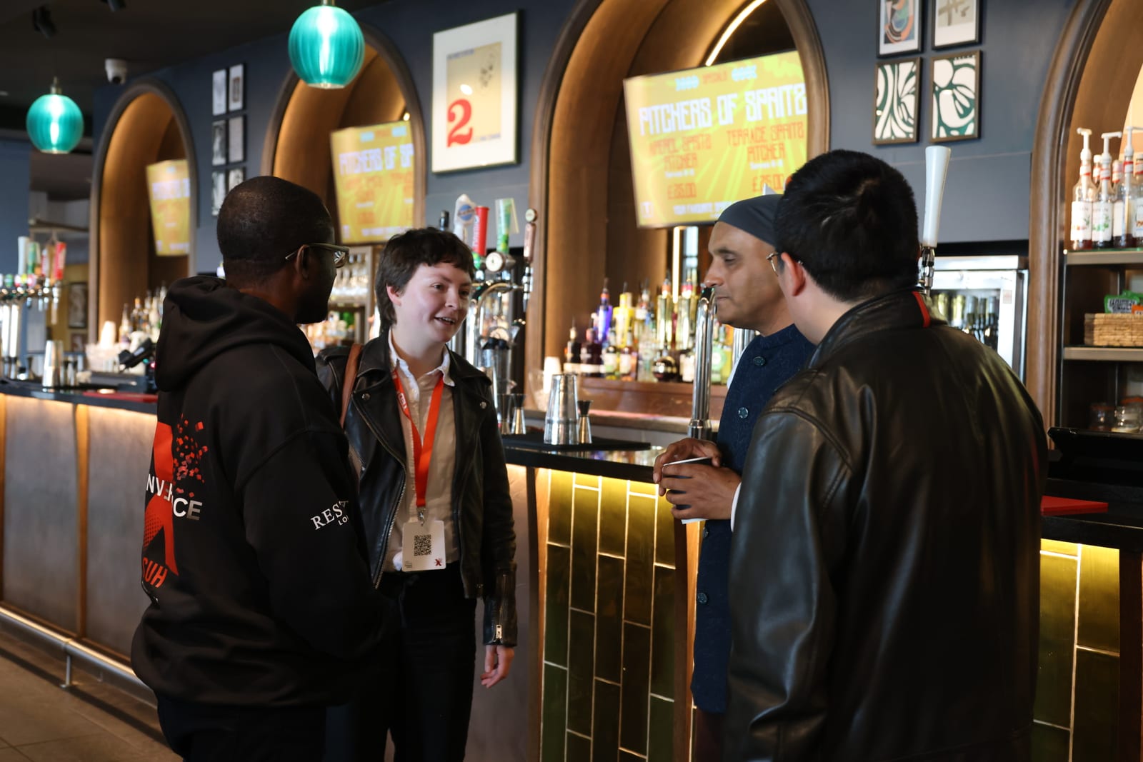 Attendees and team members chatting at the bar during a networking break